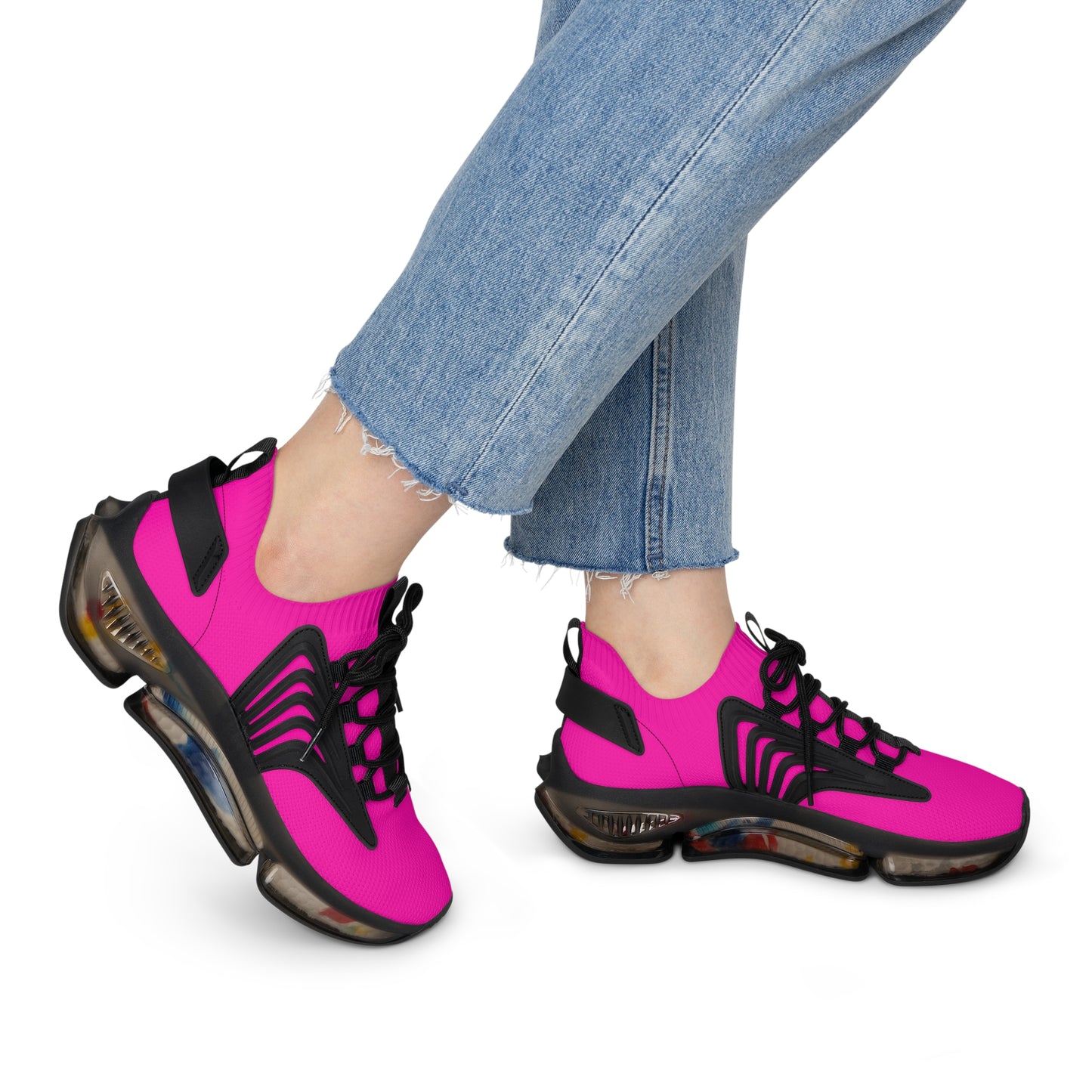 Pink and black sneakers worn with blue jeans on a white background