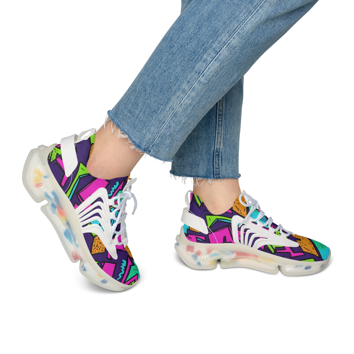 Colorful sneakers with abstract patterns worn with blue jeans on a white background
