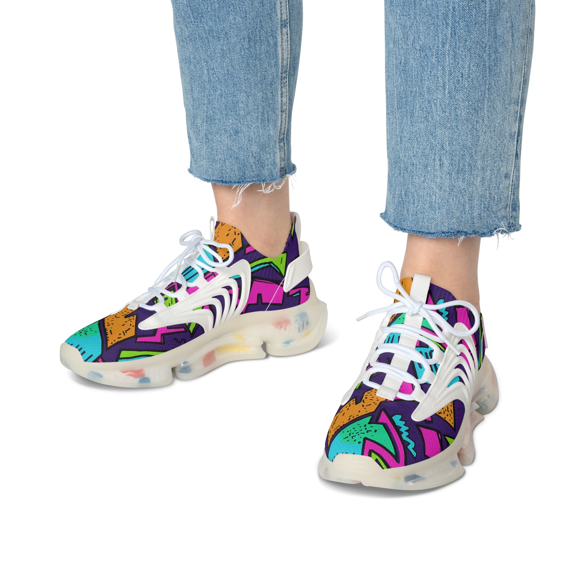 Colorful sneakers with abstract patterns worn with blue jeans on a white background