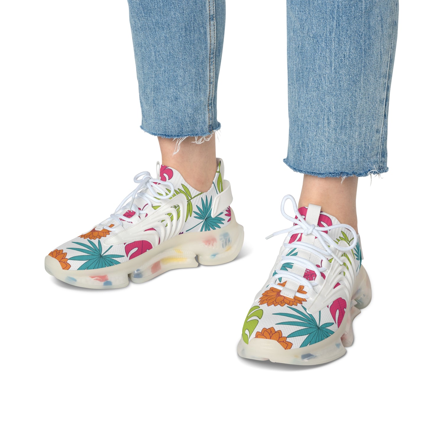 White sneakers with colorful floral pattern worn with blue jeans on a white background