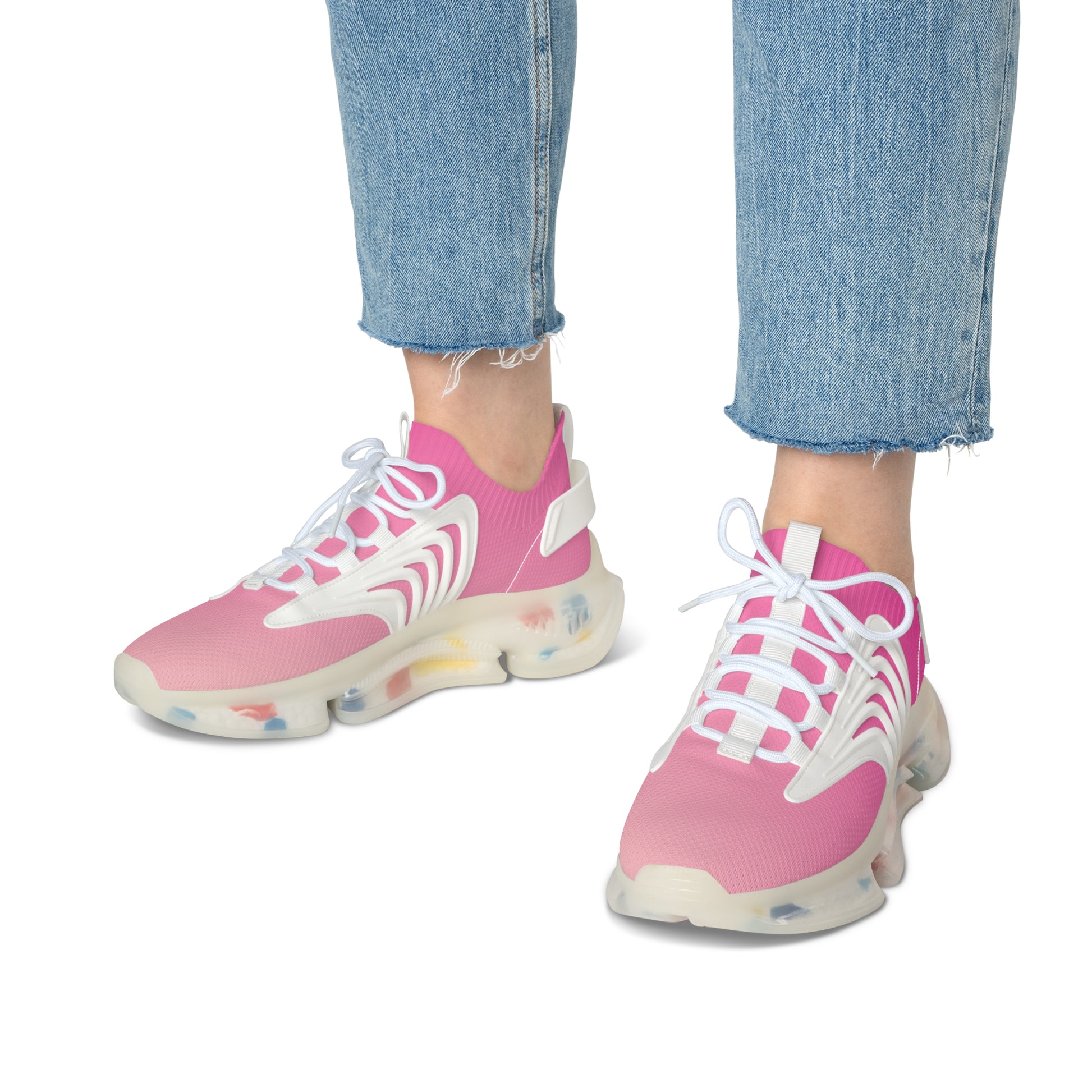 Pink sneakers with white laces worn with blue jeans on a white background
