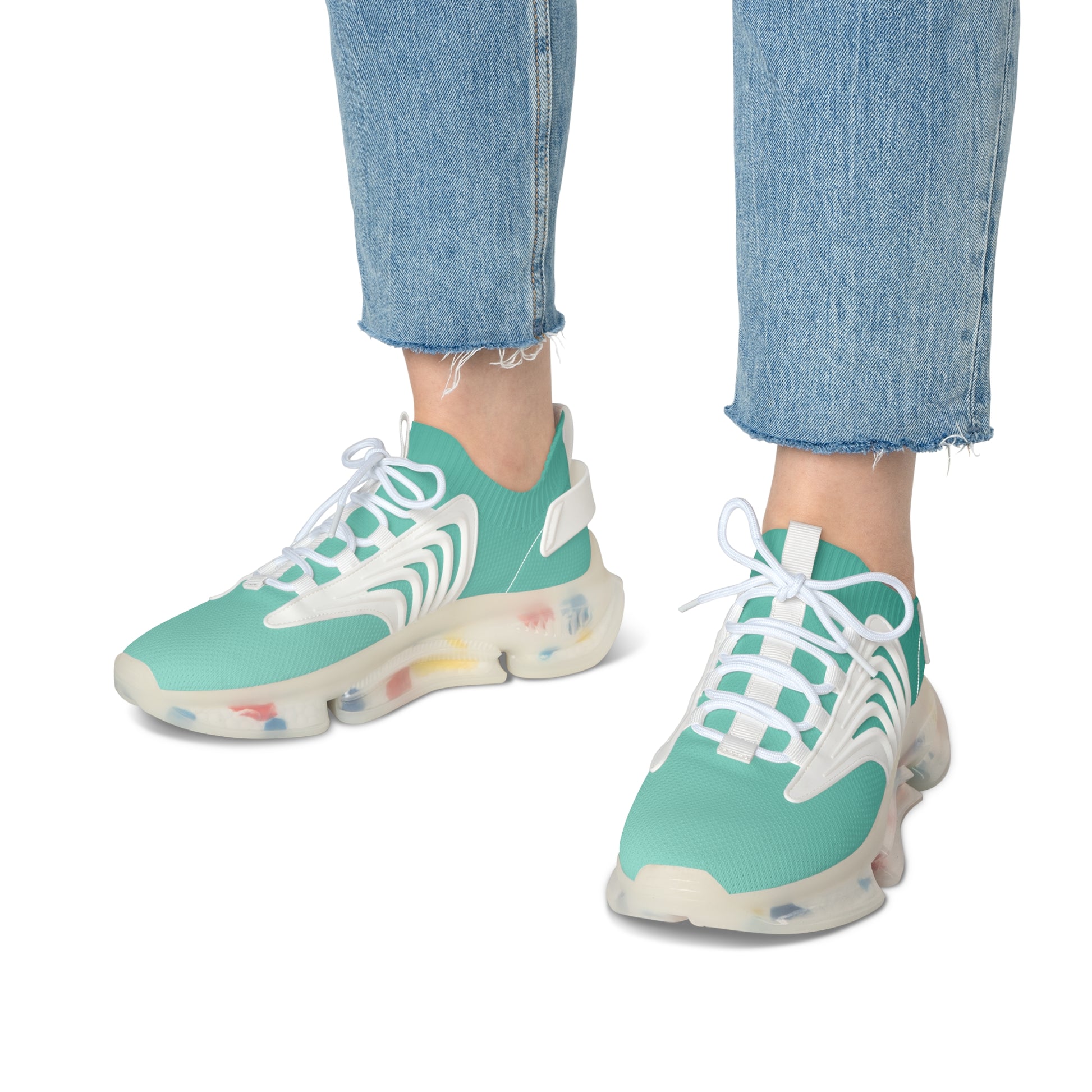 Teal sneakers with white laces worn with blue jeans on a white background