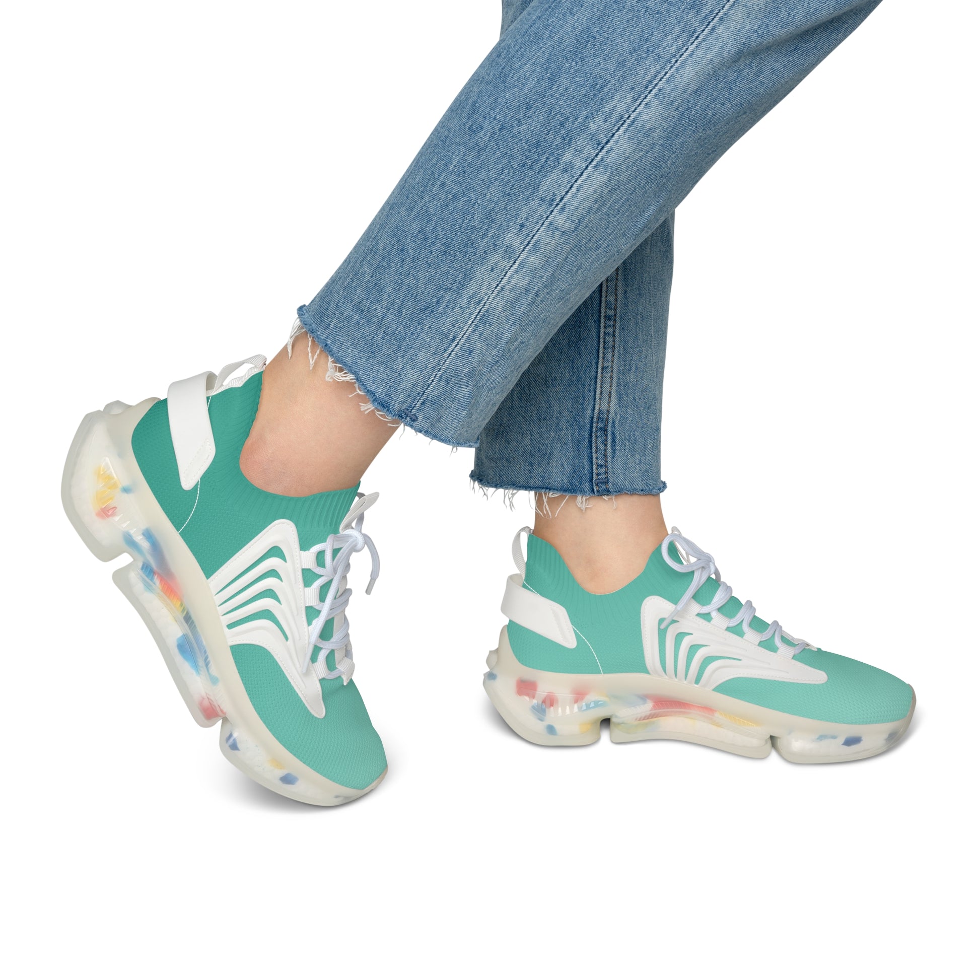 Teal sneakers with colorful sole worn with blue jeans on a white background