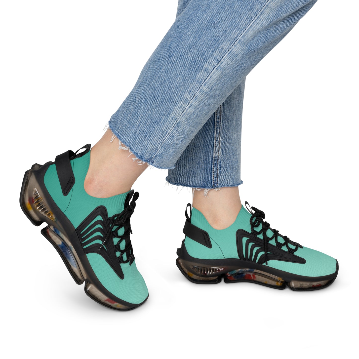 Teal and black sneakers worn with blue jeans on a white background