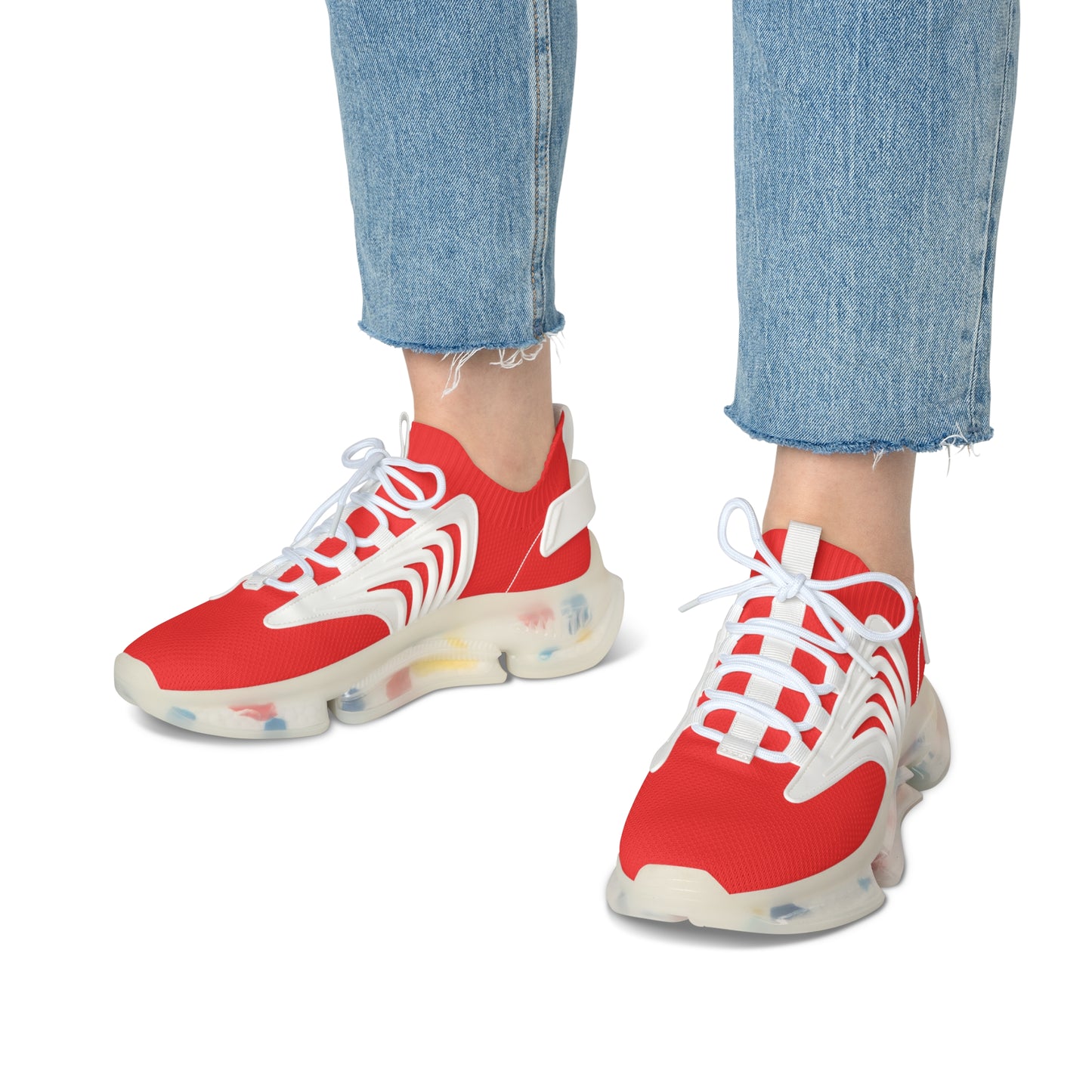 Red sneakers with white laces worn with blue jeans on a white background